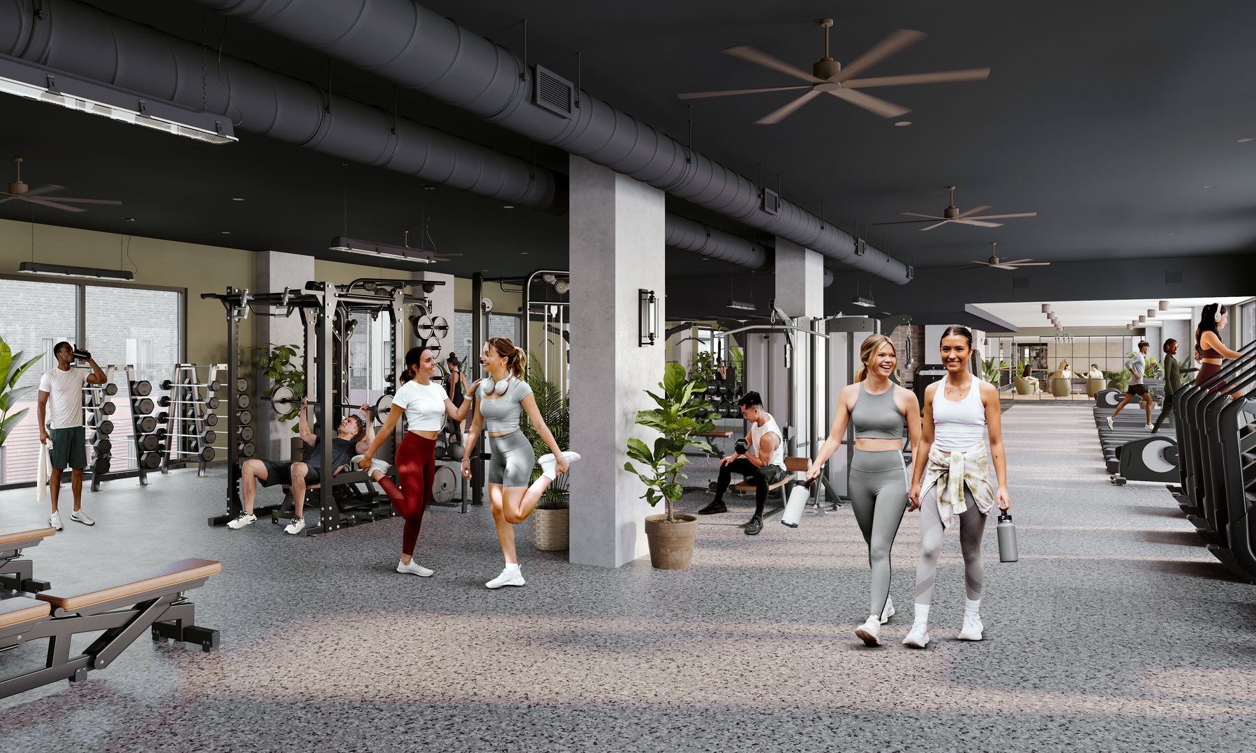 A modern gym in off campus apartments TAMU with people exercising on weight machines, stretching, and jogging on treadmills. Two women in workout clothes are walking and smiling in the bright, plant-filled space with fitness equipment throughout.