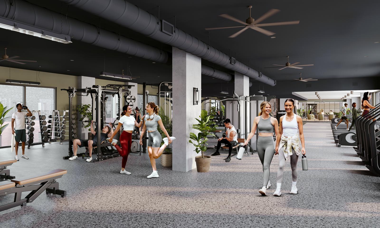 A spacious gym with people working out on various equipment, stretching, and walking. Some are lifting weights, others are using cardio machines. The space is well-lit with fans, potted plants, and modern furnishings.