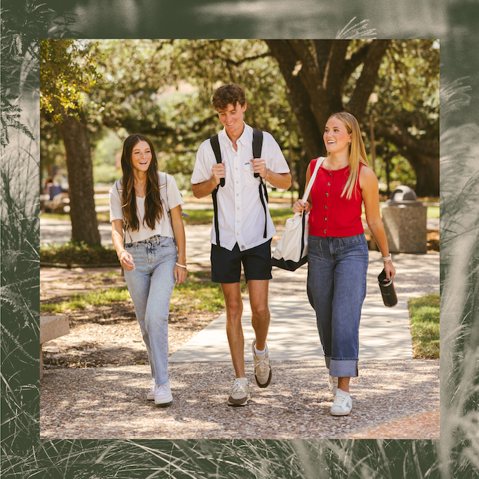 Three young adults walk together outdoors on a sunny day, smiling and talking. Carrying backpacks near apartments near Texas A&M University, they’re dressed casually as they stroll through a park-like setting with trees in the background.