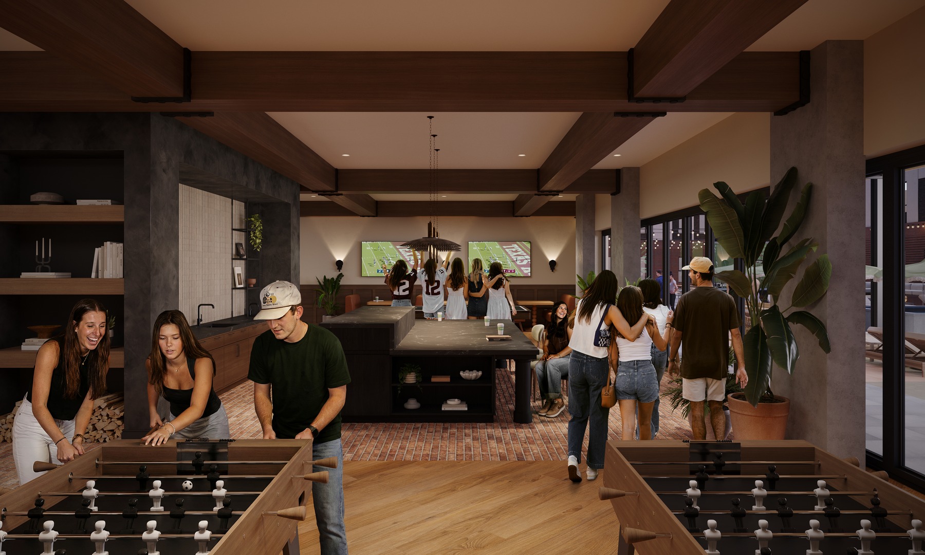 A group of young people socializes in a modern lounge with foosball tables, large windows, plants, and a TV showing a football game. Some play foosball, while others gather around the island or watch the TV.