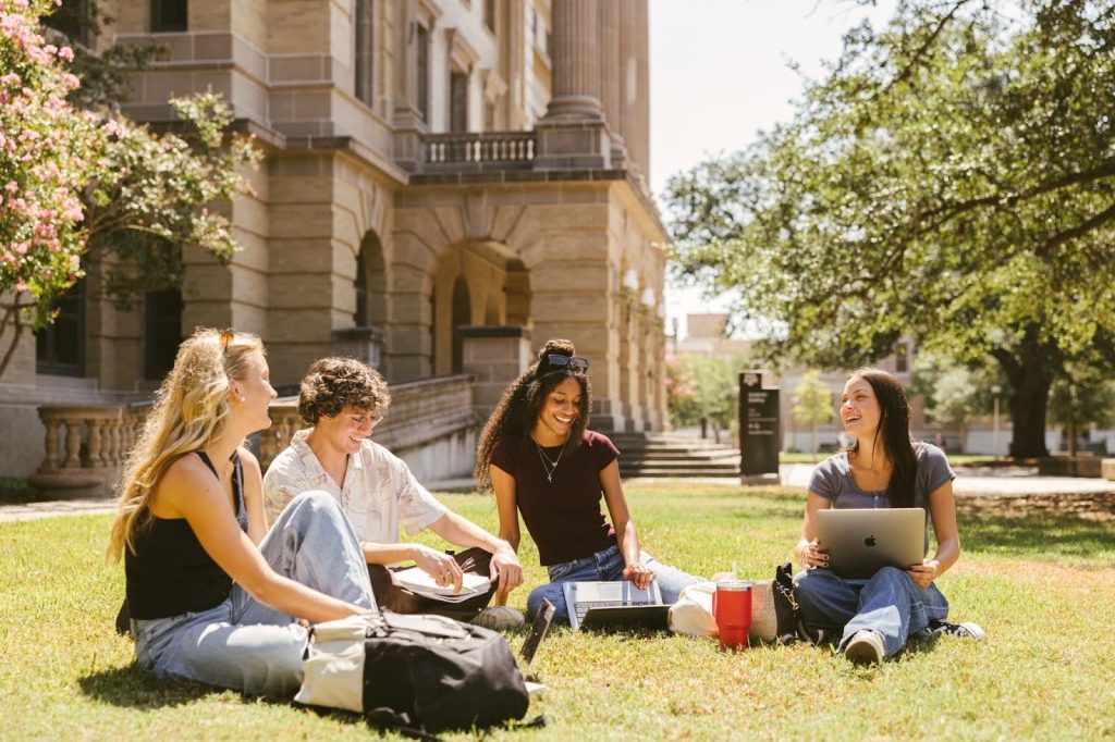 Students work on laptops on the lawn at Texas A&M.