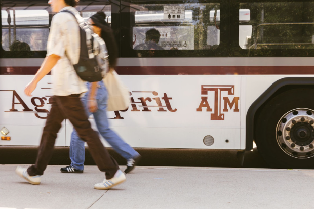 Texas A&M students walk in front of the Aggie Spirit bus in College Station.