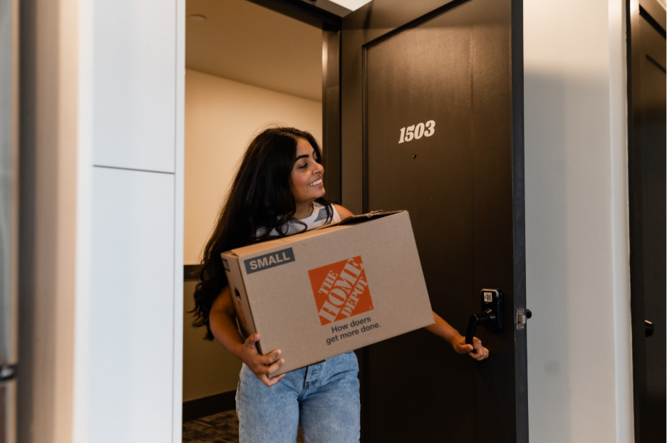 A new resident enters The Jay with their moving boxes in College Station. 