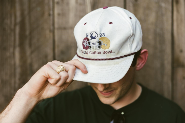 Texas A&M student wearing Aggie Ring and Mobil Cotton Bowl hat with Texas A&M on it.
