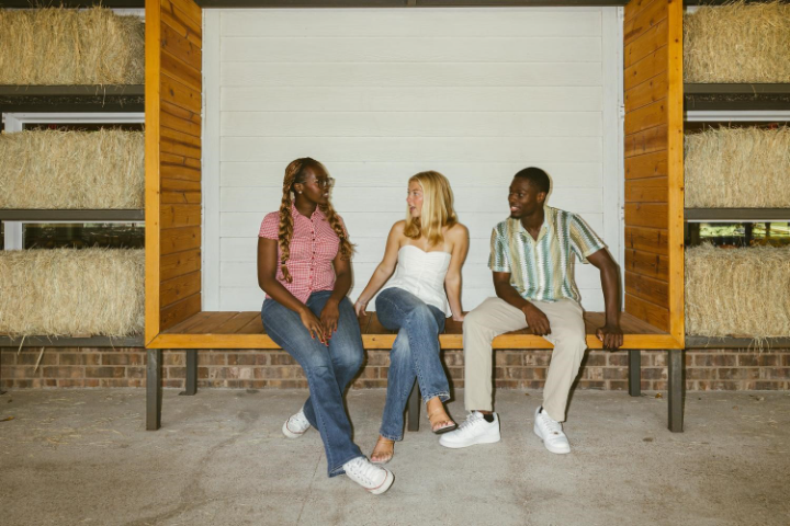 Texas A&M students discussing student apartments in College Station on a bench.  
