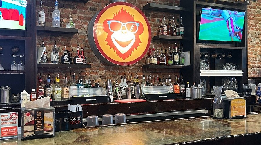 Bar-top and neon logo sign with TVs at Proudest Monkey in College Station.