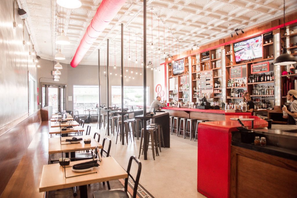 Industrial interior with red accent counter and trim at Rx Pizza near Texas A&M.