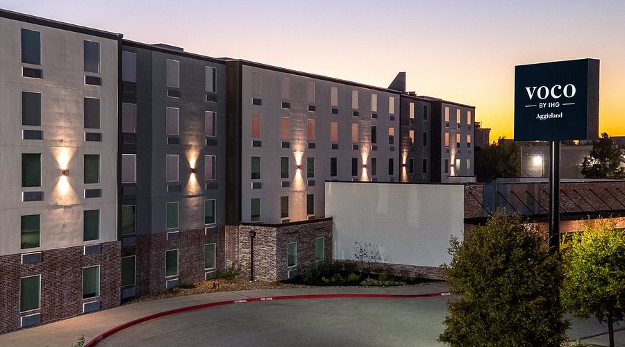 Exterior view of voco College Station Aggieland by IHG at sunset.