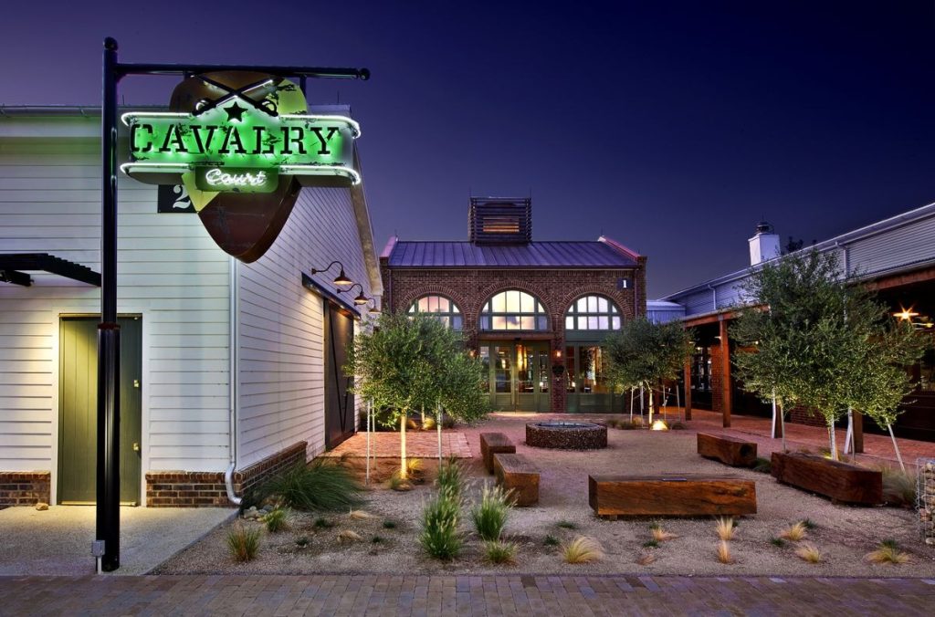 Calvary Court Hotel in College Station at night with an industrial-rustic exterior complimented with greenery.