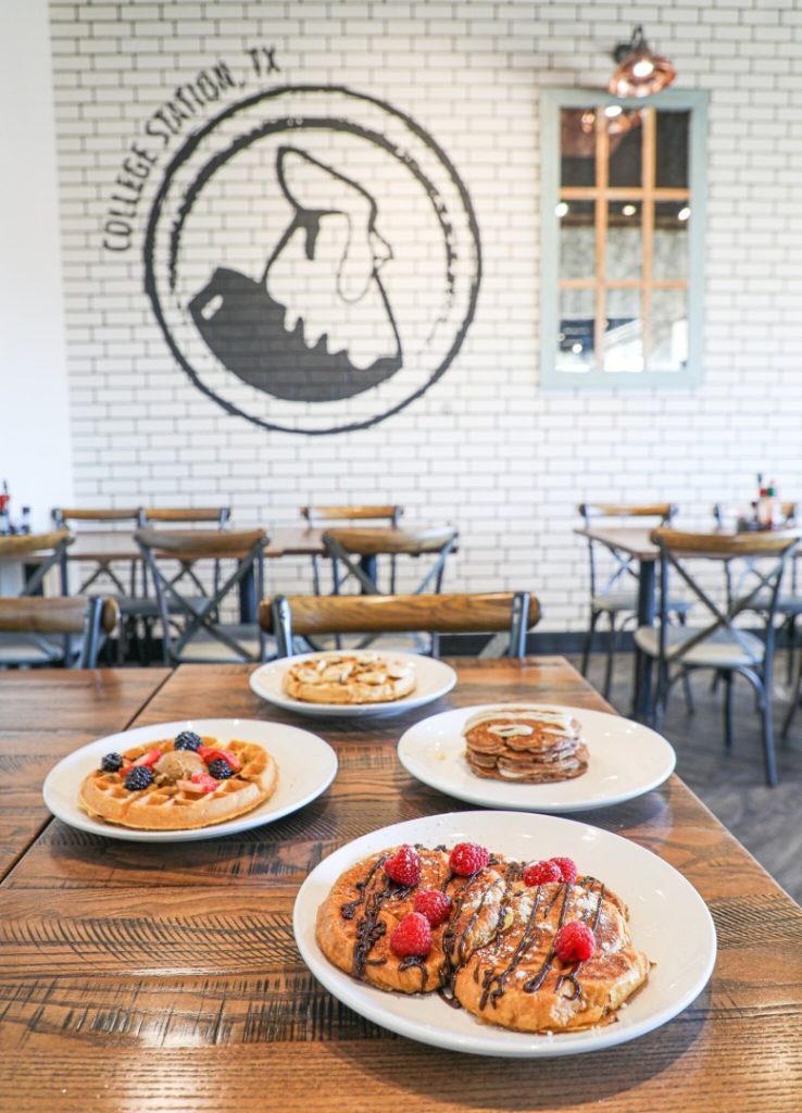 White brick wall with Another Broken Egg Cafe College Station logo.